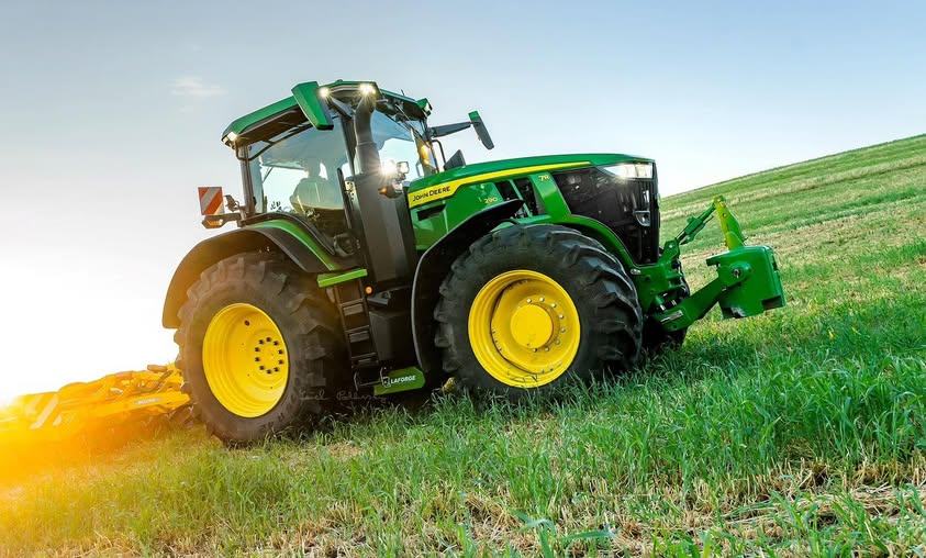 Tractor John Deere lucrand pe camp, la apus
