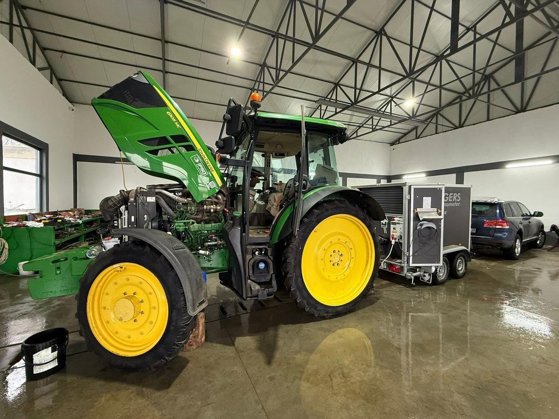 Tractor John Deere 6105MC verde, cu capota ridicată, în atelier